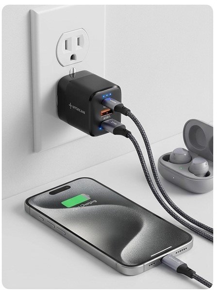 Interlink Aura 25W dual port wall charger plugged into a wall outlet charging a smartphone and wireless earbuds simultaneously